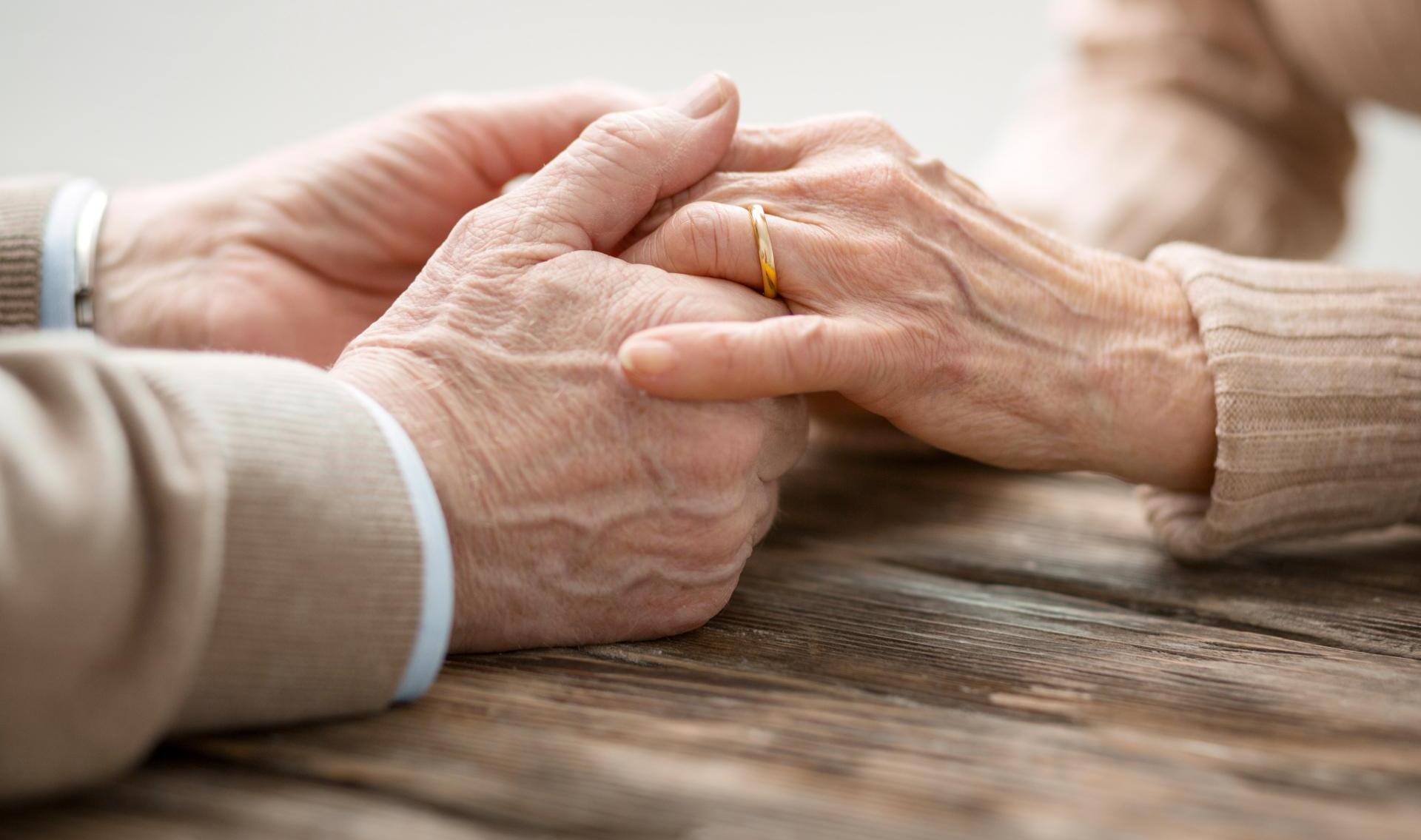 Aged married couple sitting together while holding hands