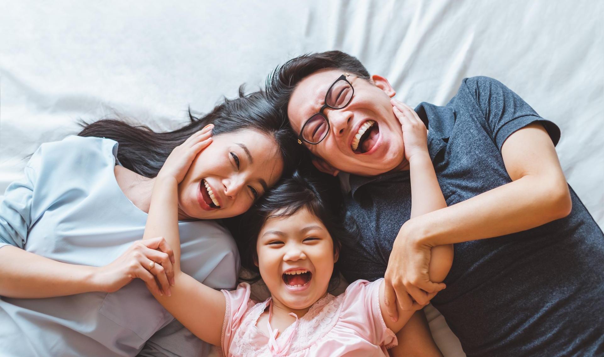 Happy family laying on bed smiling