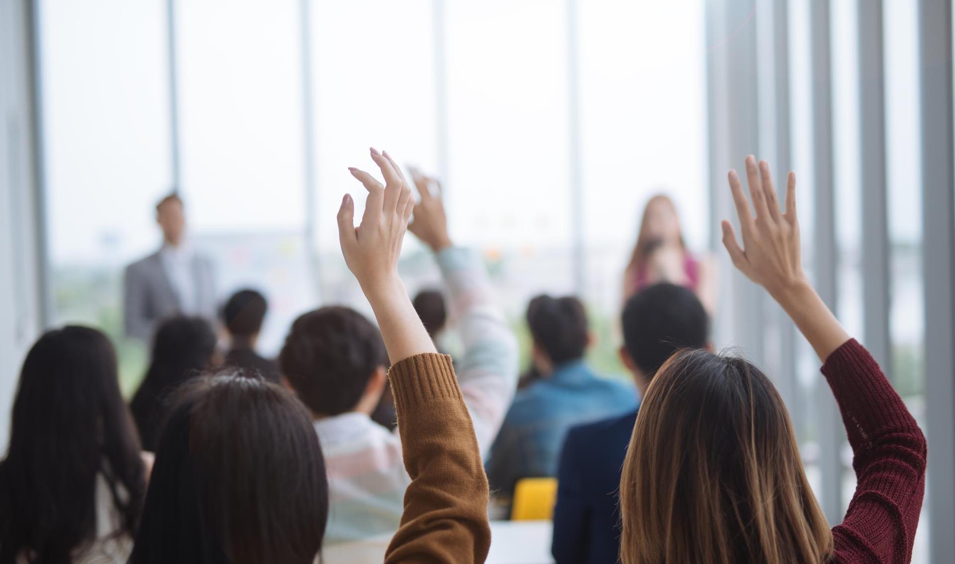 Raised up hands and arms of large group in seminar class room to agree with speaker at a seminar meeting room