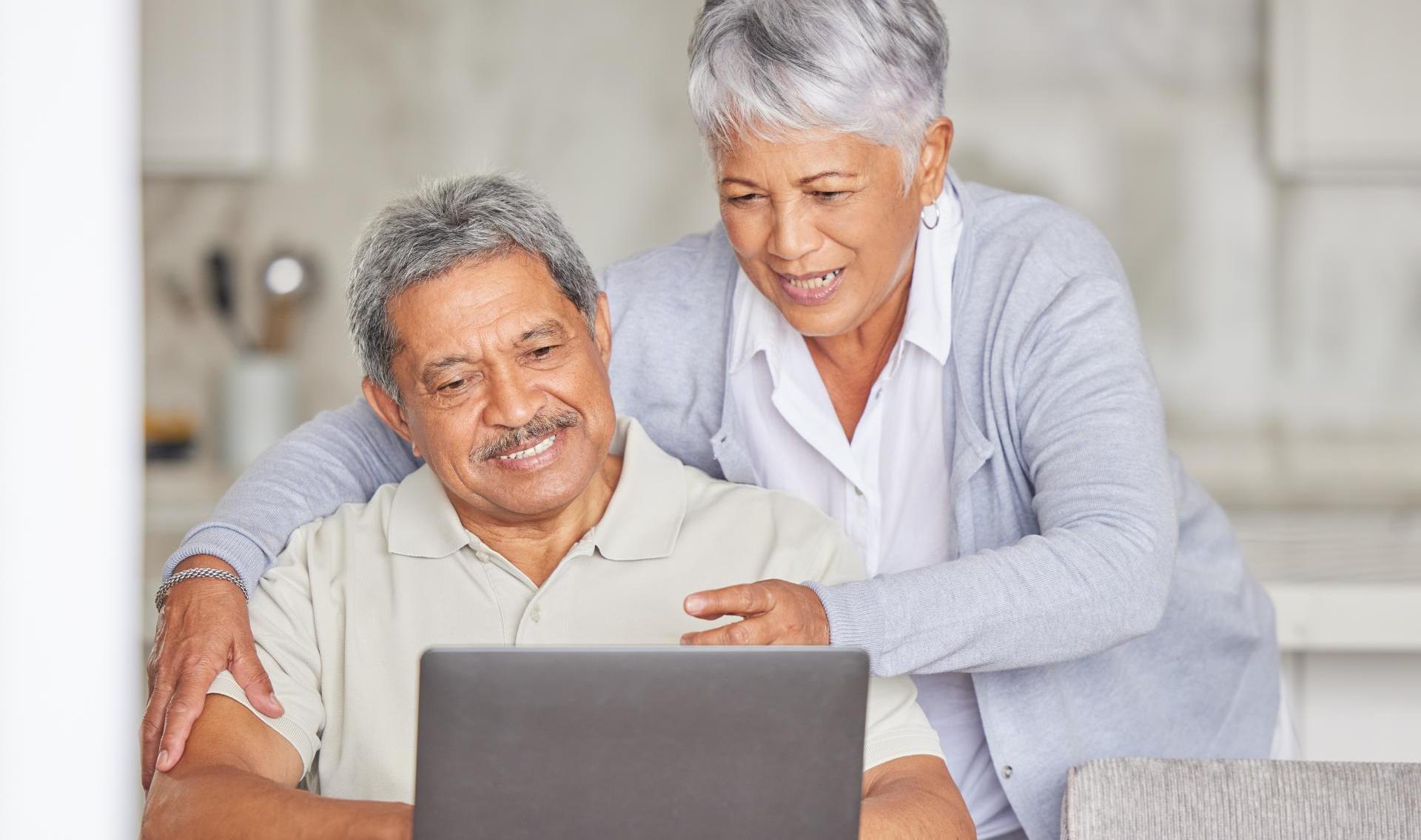 Happy elderly woman with a relaxed husband streaming or browsing online at home