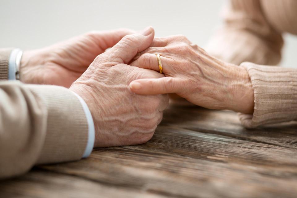Aged married couple sitting together while holding hands