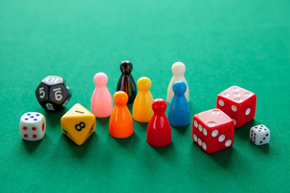 Colored game figures chips for board games. Collection of dice cubes on green table