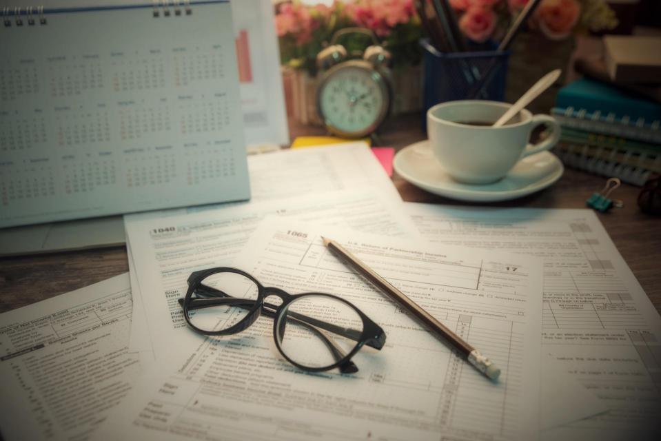 Tax forms accompanied  by cup of coffee, pencil , and eyeglasses.
