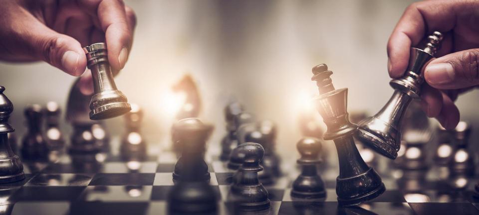 Two gentlemen moving chess pieces on chess board