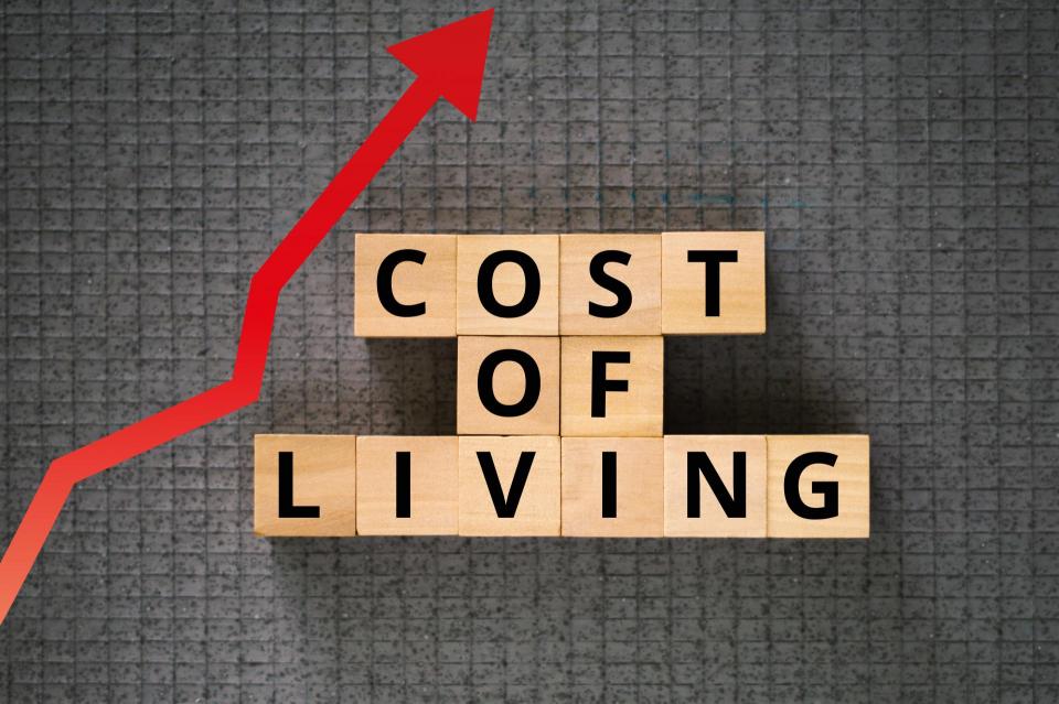 Cost of Living words on cubes dark rough background with red arrow chart