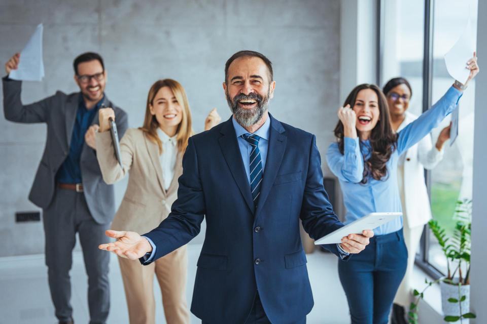 Euphoric excited business team celebrate corporate victory together in office