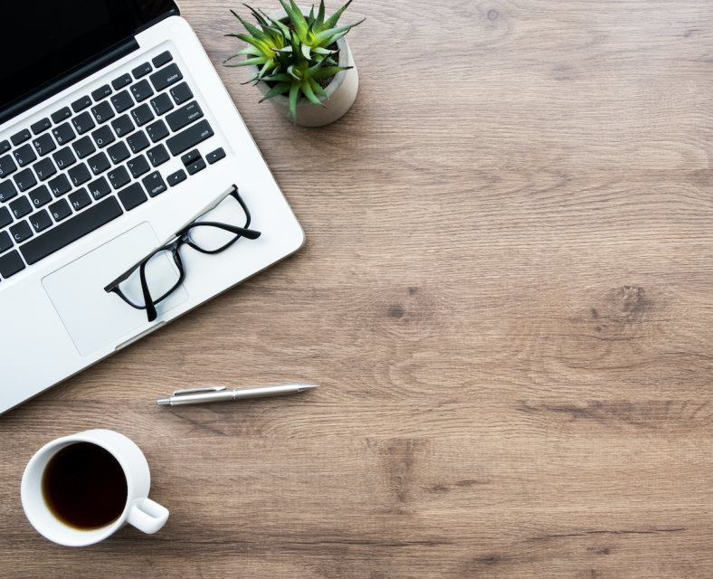 Laptop, coffee mug, and eyeglasses on desk