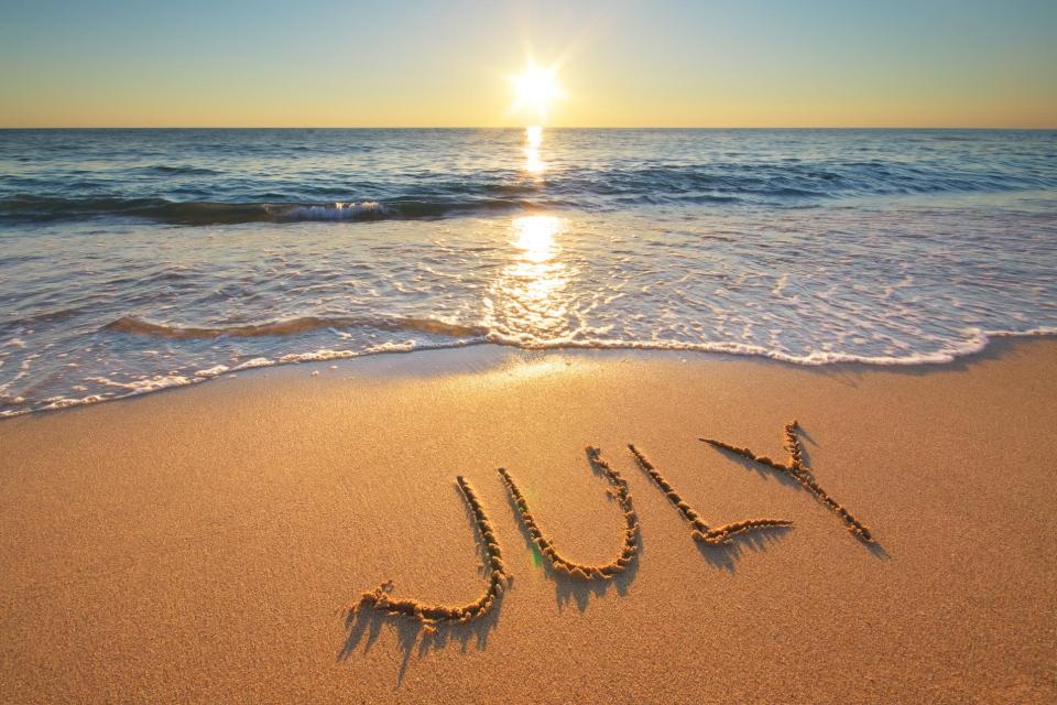 Sunset at the beach, with July written in the sand.