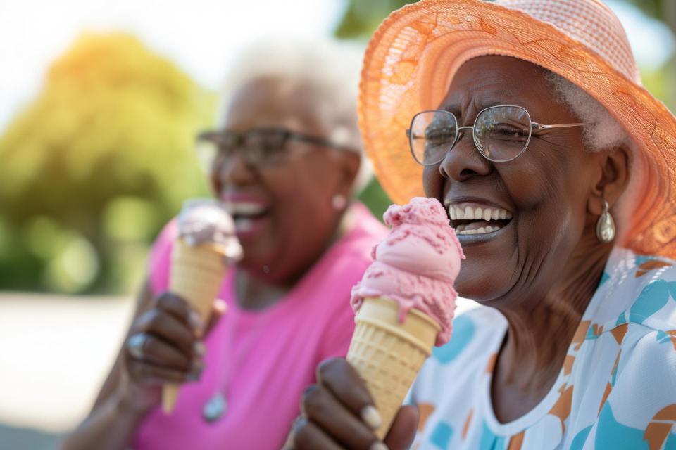 Couple of cheerful elderly female friends eating ice cream outdoors .on a sunny  day.