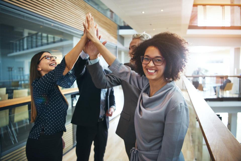 Cheerful woman celebrating with colleagues in office