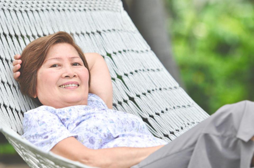 Woman relaxing and smiling on hammock, Summer garden with hanging hammock for relaxation on long weekend holiday.