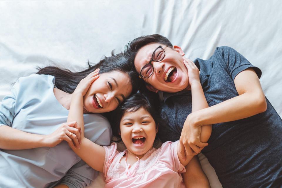 Happy family laying on bed smiling