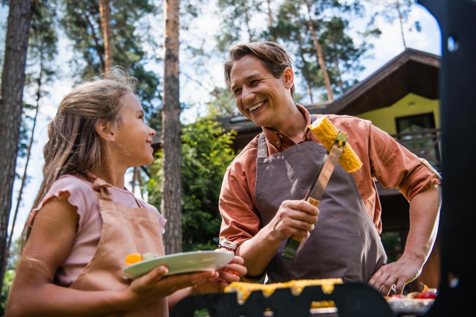 Father and daughter grilling corn