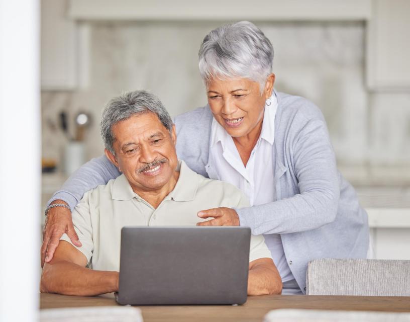Happy elderly woman with a relaxed husband streaming or browsing online at home