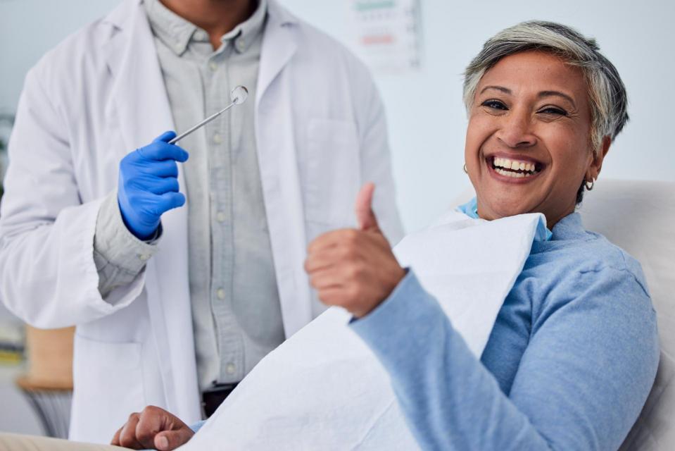 Happy woman with thumbs up in dentist chair.