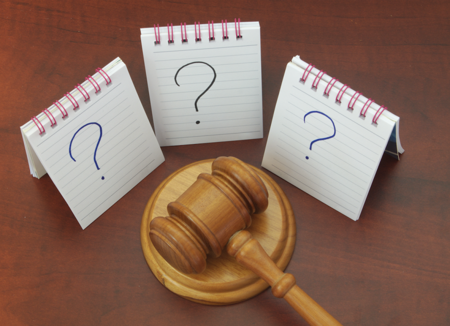 gavel surrounded by notepads with question marks