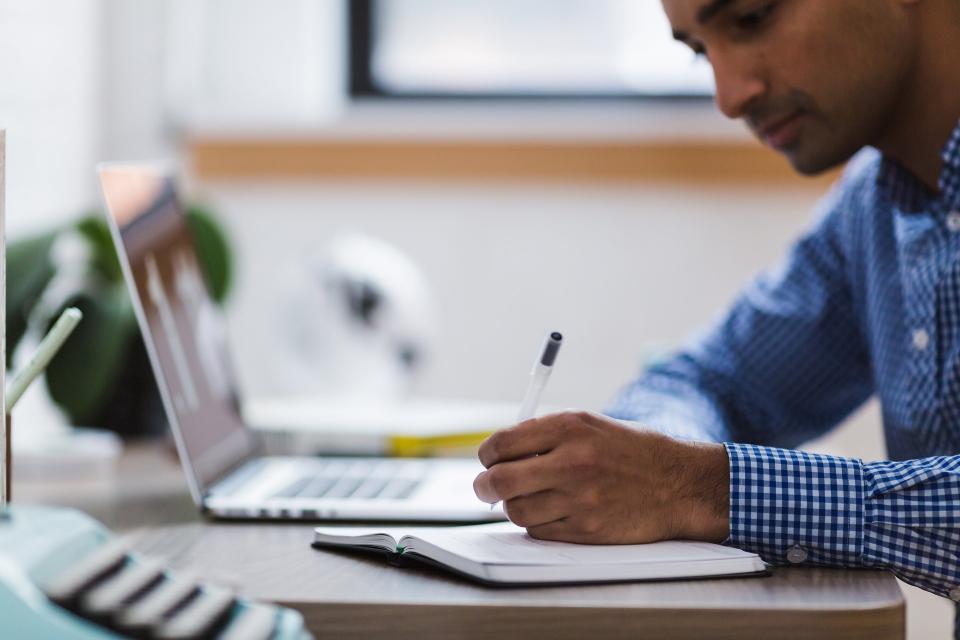 man writing on notepad